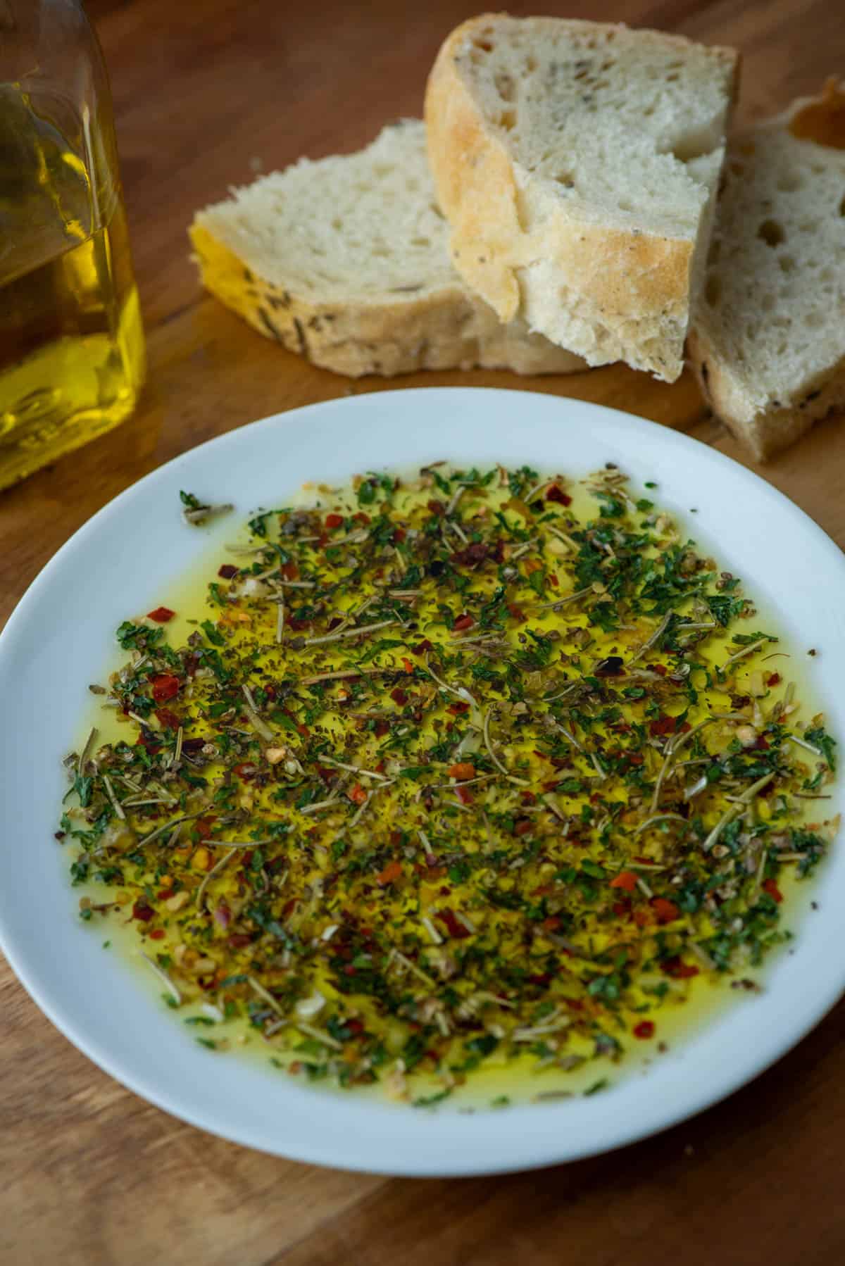 bread dipper seasoning in oil on plate with bread and olive oil in the background