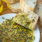 Plate with bread dipper seasoning in oil and bread in the background