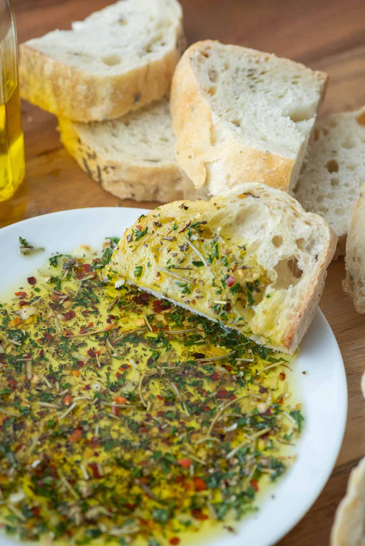 Plate with bread dipper seasoning in oil and bread in the background