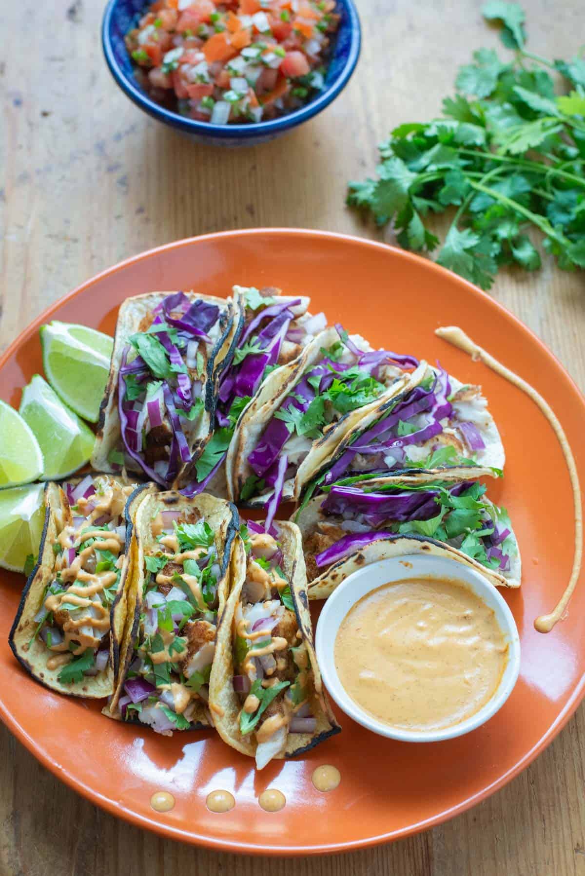 Fish Tacos on Plate with Cilantro and pico de Gallo in background