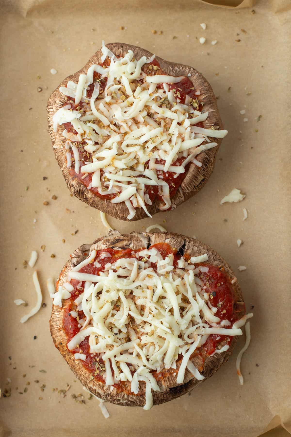 Two pre-cooked portobello mushrooms on a baking sheet