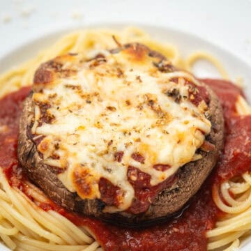 Close up of portobello mushroom parmesan on pasta on a plate