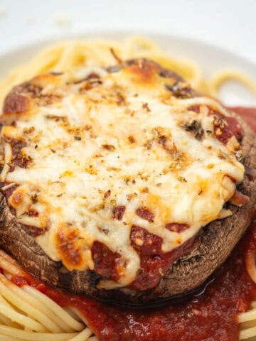 Close up of portobello mushroom parmesan on pasta on a plate