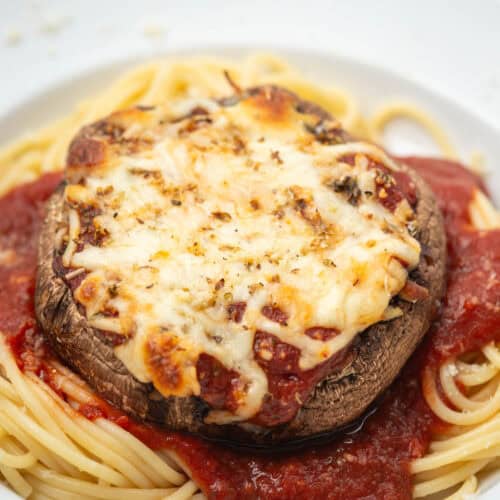 Close up of portobello mushroom parmesan on pasta on a plate