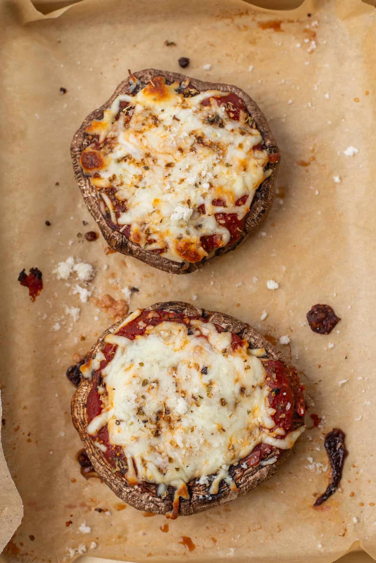 Two cooked portobello mushrooms on baking sheet