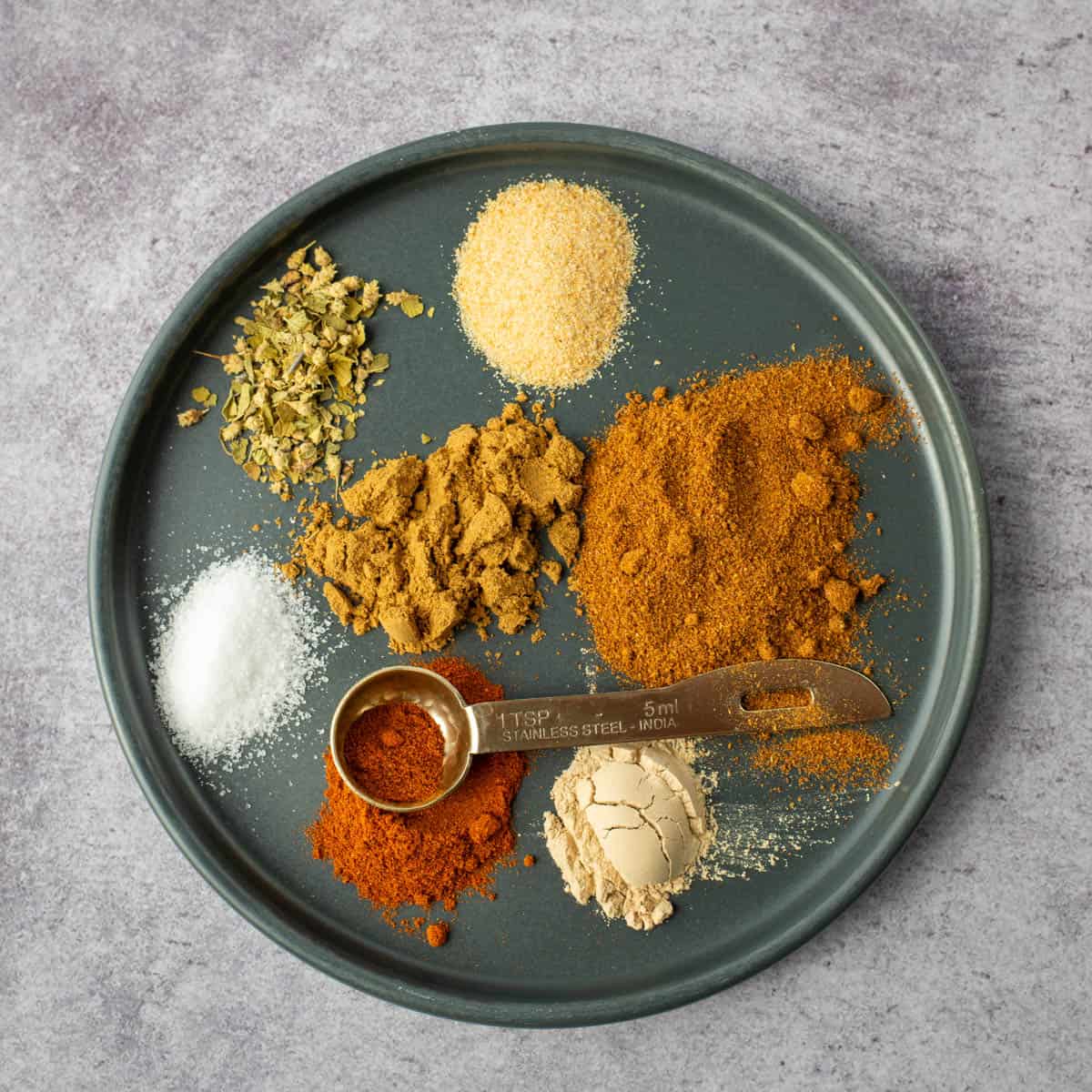 Plate with the six loose spices needed to make homemade taco seasoning 