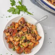 Gluten Free Sausage Stuffing in bowl with spoon with serving bowl in background