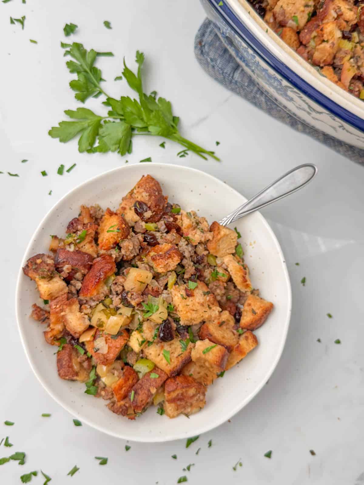 Gluten Free Sausage Stuffing in bowl with spoon with serving bowl in background