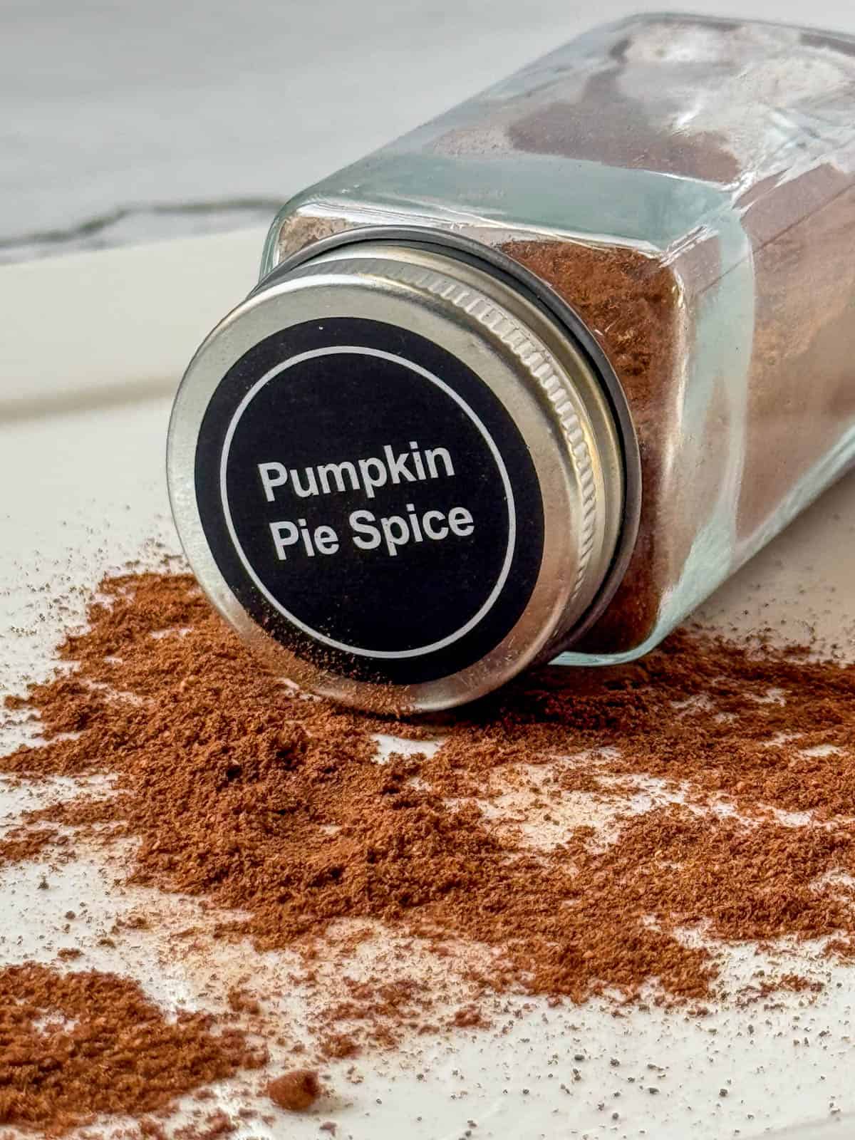 Jar of Pumpkin Pie Spice tipped on its side with loose spices in front