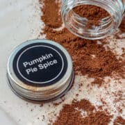 Jar of opened Pumpkin Pie Spice tipped on its side with loose spices in front