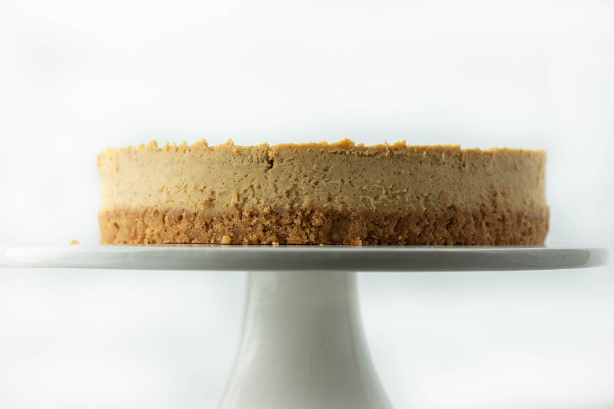 Side angle of pumpkin spice cheesecake on cake stand