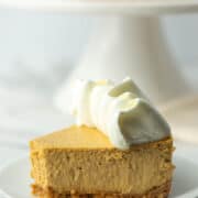 Slice of pumpkin spice cheesecake with rest of cheesecake in background