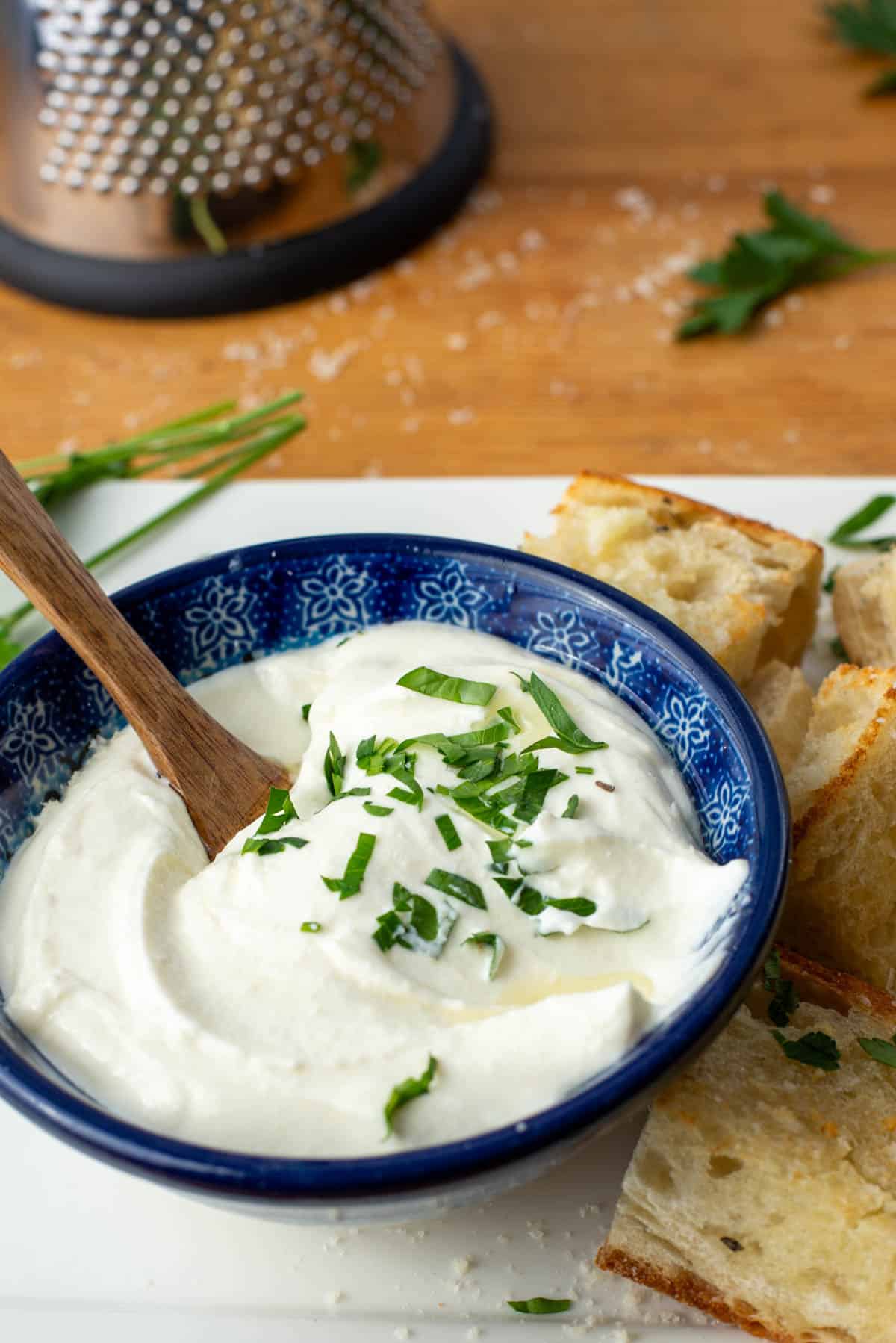 White truffle whipped ricotta dip with garlic bread and grater in background