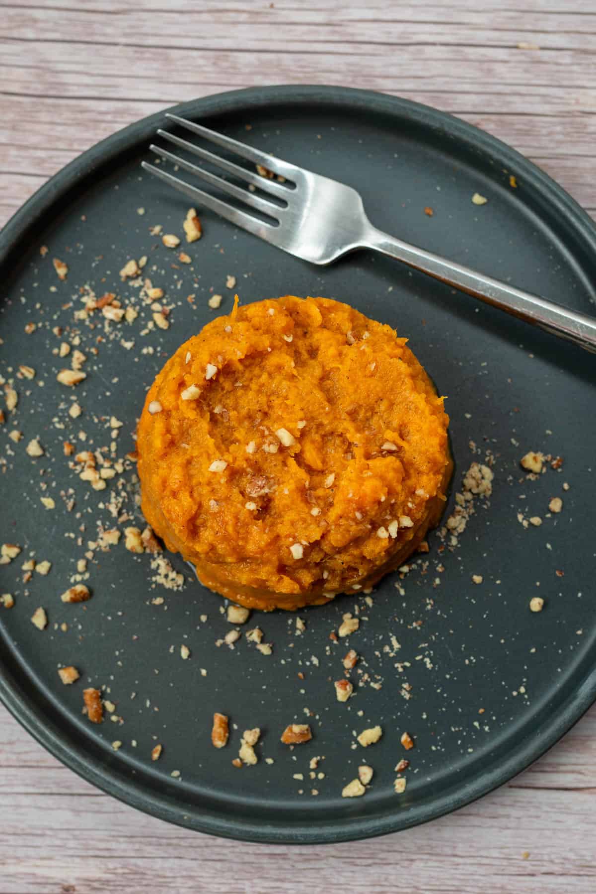 Bourbon sweet potatoes on a plate with a fork and garnished with pecan pieces