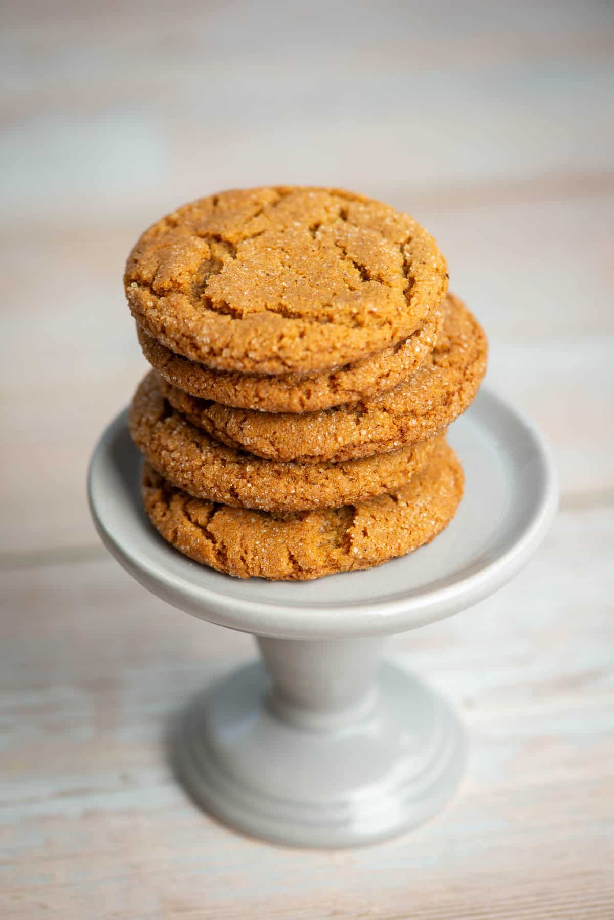 5 chewy ginger molasses cookies stacked on a small pedestal