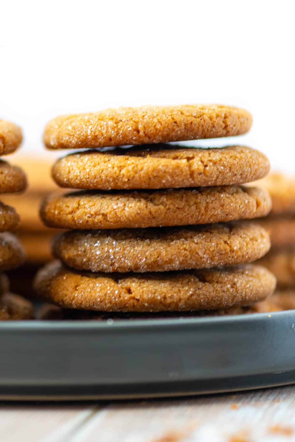 close up photo of 5 chewy ginger molasses cookies stacked on a plate