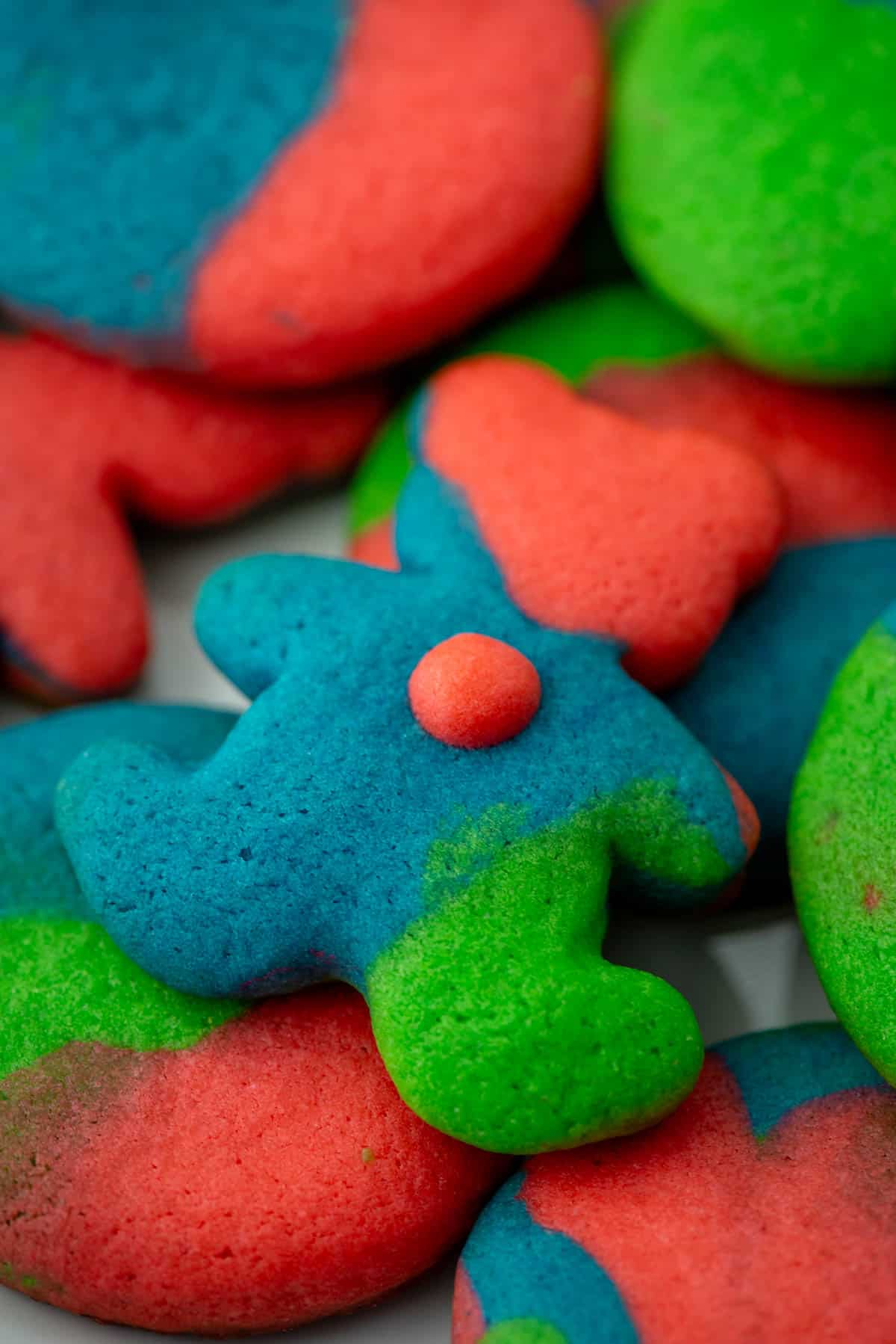 Close up photo of teddy bear colored cookie dough sugar cookie on top of other colored sugar cookies