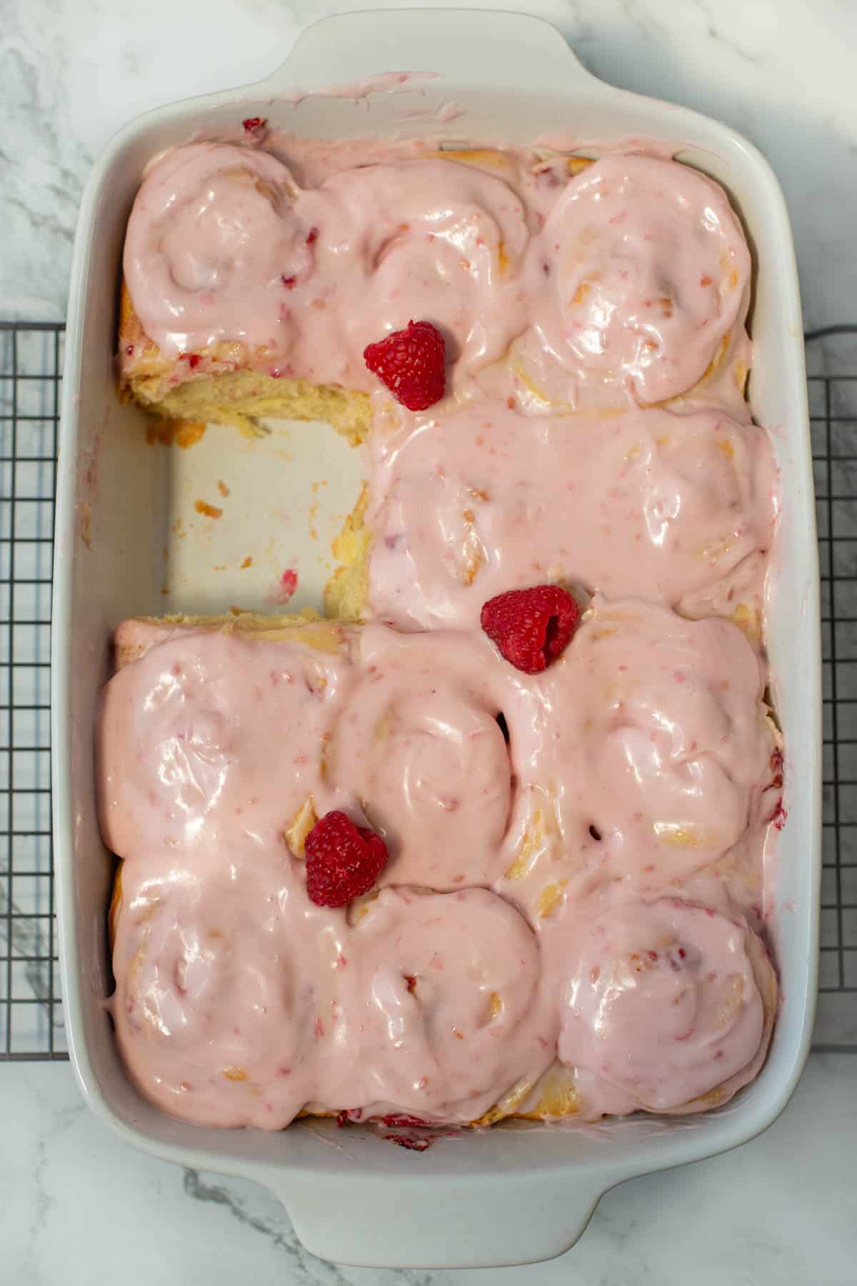 Top view of pan of lemon raspberry sweet rolls with one missing