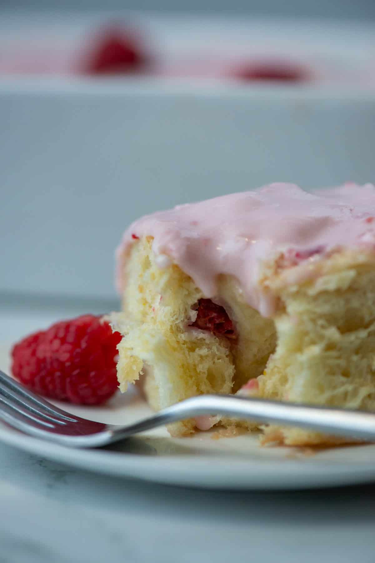 Side view of lemon raspberry sweet roll on a plate