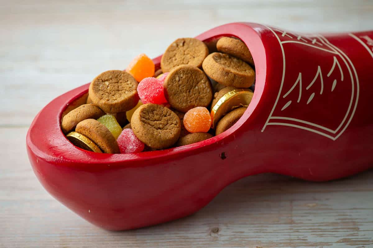 Close up photo of Dutch wooden shoe filled with peppernut cookies, spiced gum drop candies and gold coins