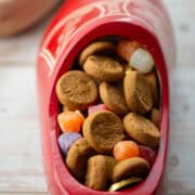 Close up photo of Dutch wooden shoe filled with peppernut cookies, spiced gum drop candies and gold coins with additional shoe in background