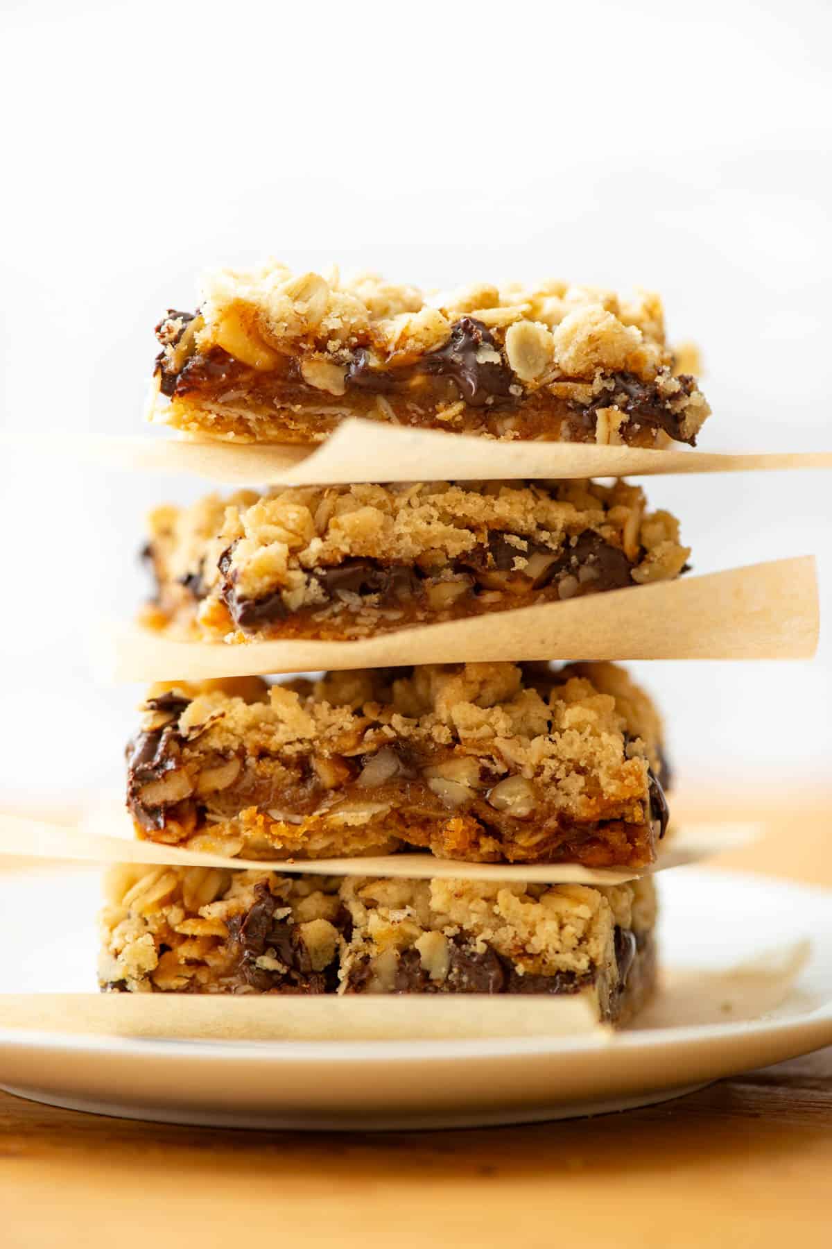 Stack of 4 cut Carmelita cookie bars with parchment paper separating the cookie bars