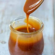 Spoon of homemade salted caramel sauce dripping into jar of homemade salted caramel sauce