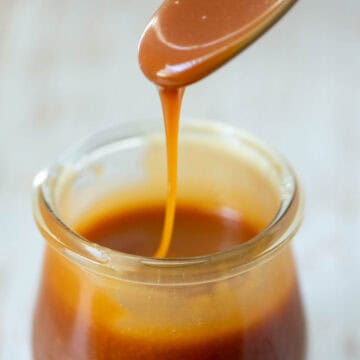 Spoon of homemade salted caramel sauce dripping into jar of homemade salted caramel sauce