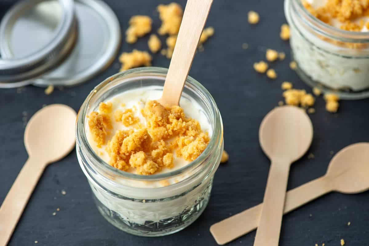 Close up photo of single serving jar of keto mini lemon cheesecake with additional jar of cheesecake in the background