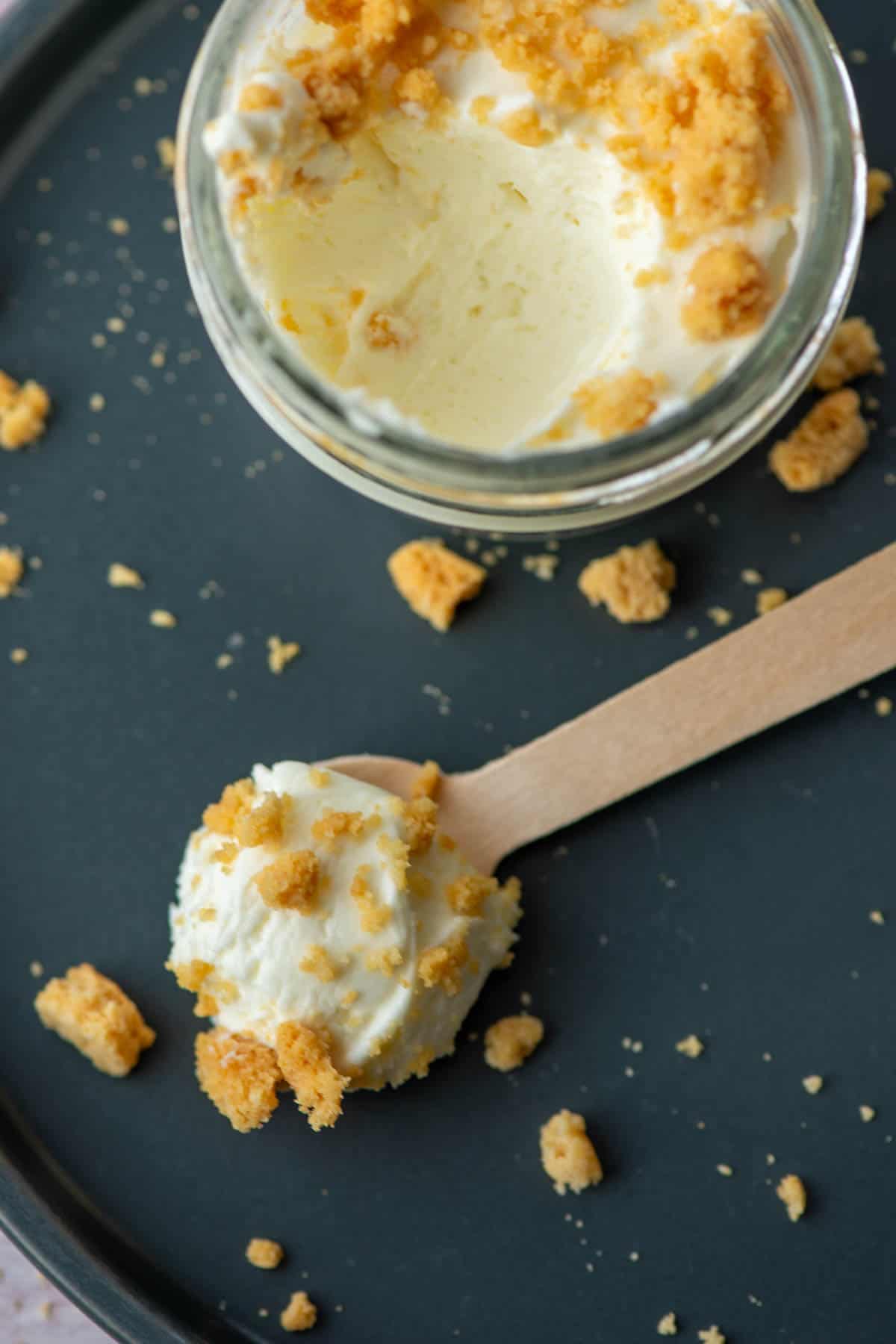 Close up photo of keto mini lemon cheesecake on a spoon with a jar of cheesecake in the background