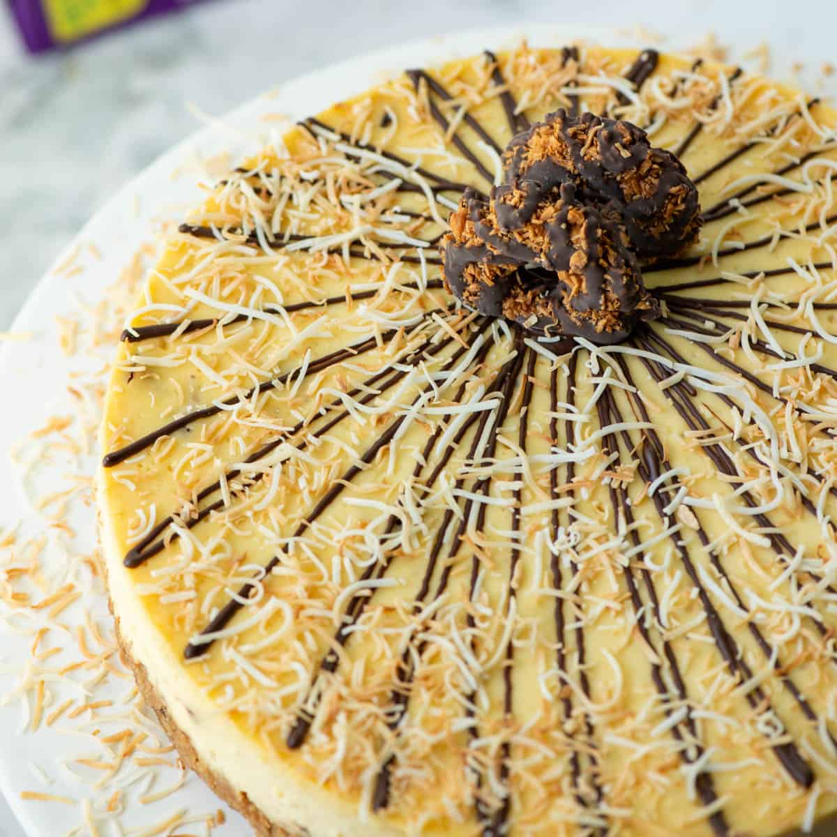 Overhead view of partial Samoas cheesecake topped with chocolate, toasted coconut and Samoas cookies