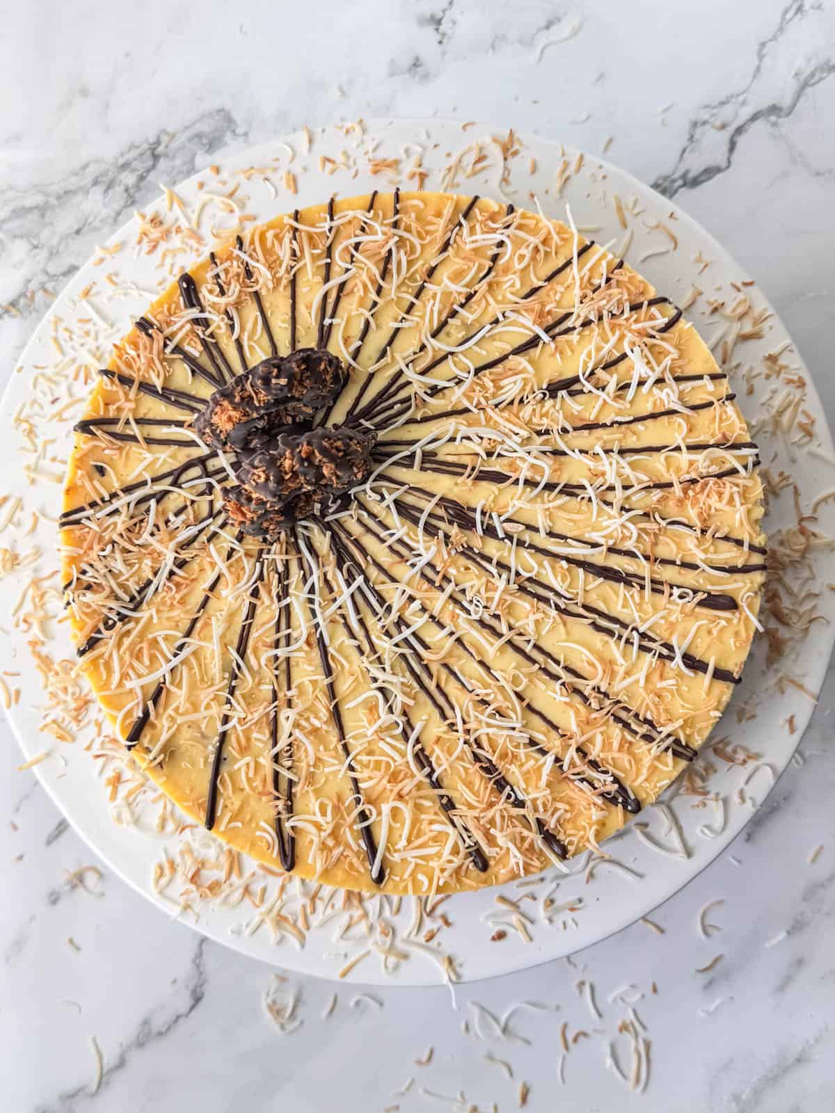 Overhead view of full Samoas cheesecake topped with chocolate, toasted coconut and Samoas cookies