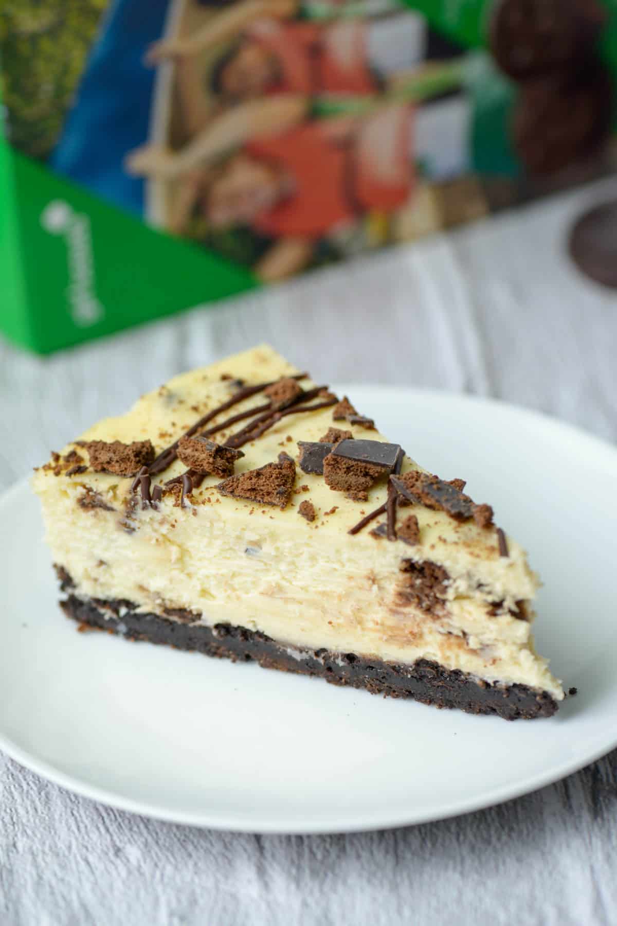 One slice of Thin Mints cheesecake with a box of Thin Mints in the background