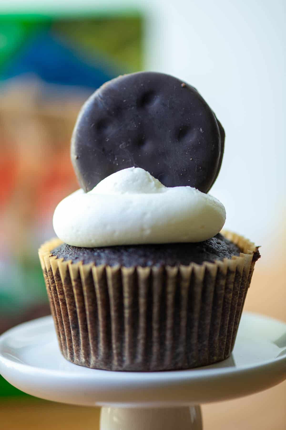 Close up photo of one Thin Mints cupcake with box of Thin Mints cookies in the background