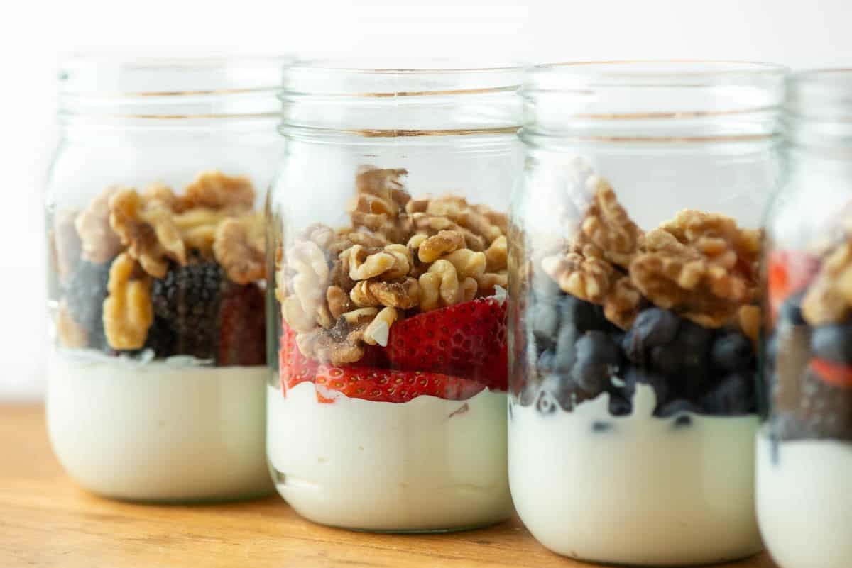 Side view of three and a half jars of berry yogurt parfaits at an angle