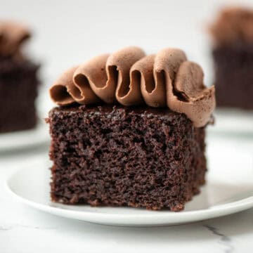 Close up photo of a slice of chocolate zucchini cake with chocolate buttercream frosting.