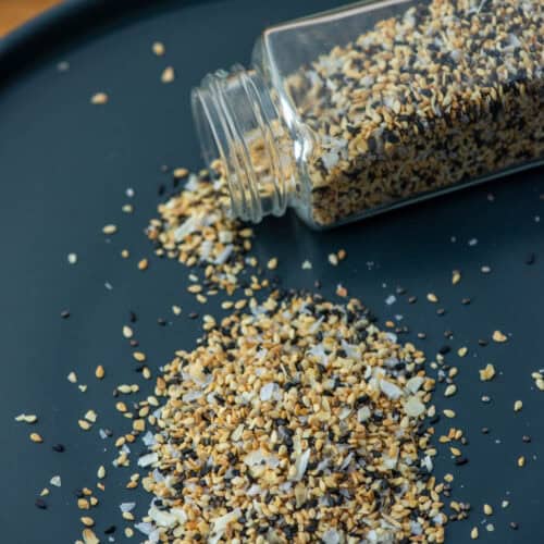Jar of everything bagel seasoning spilling out onto a gray plate