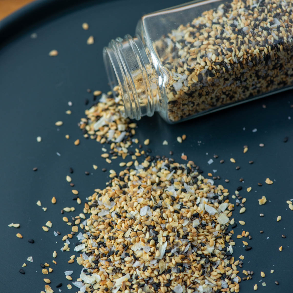 Jar of everything bagel seasoning spilling out onto a gray plate