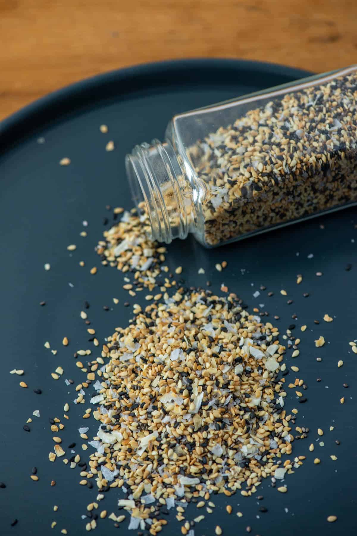 Jar of everything bagel seasoning spilling out onto a gray plate