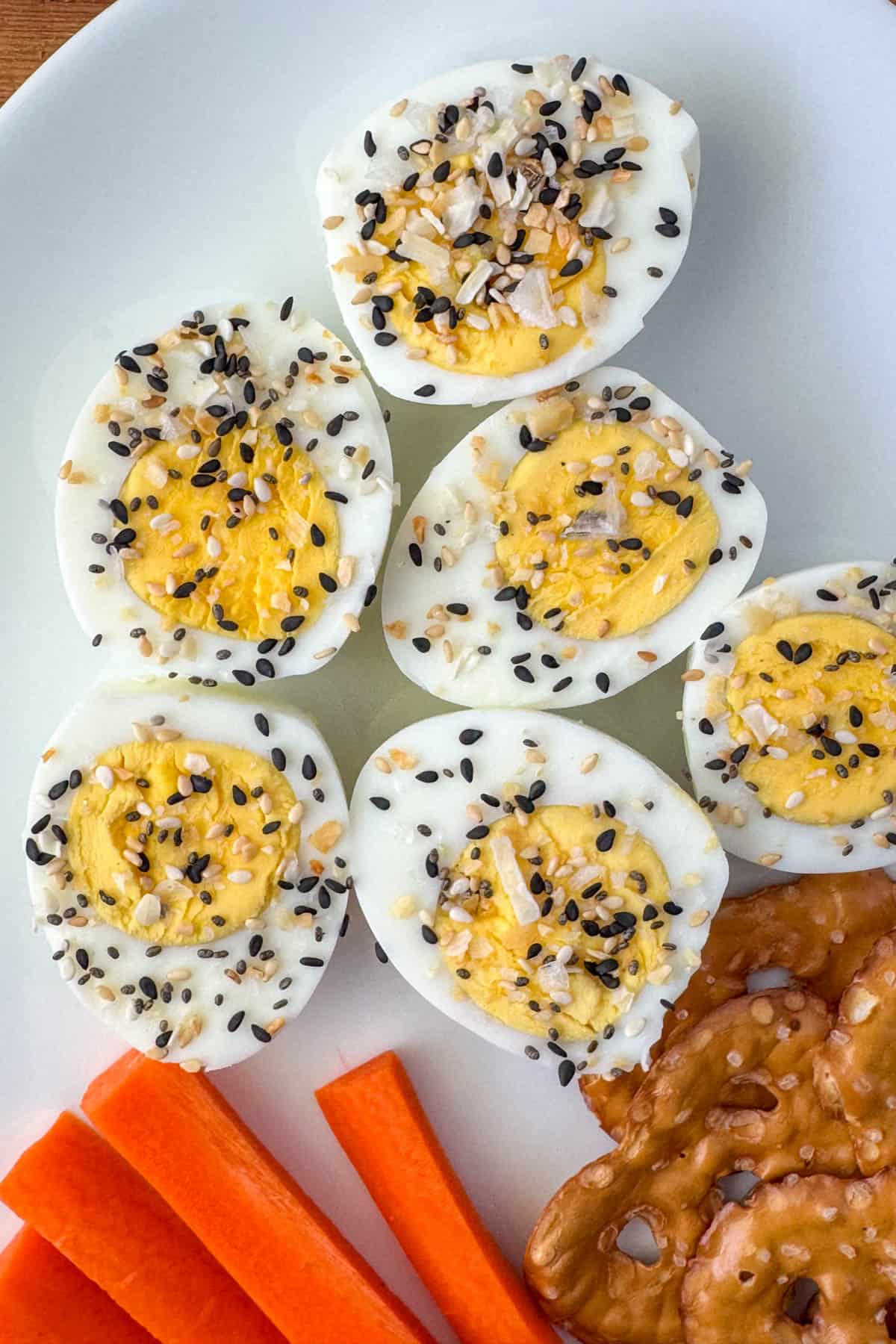 Photo of deviled eggs topping with everything but bagel seasoning plus carrots and pretzels on the side