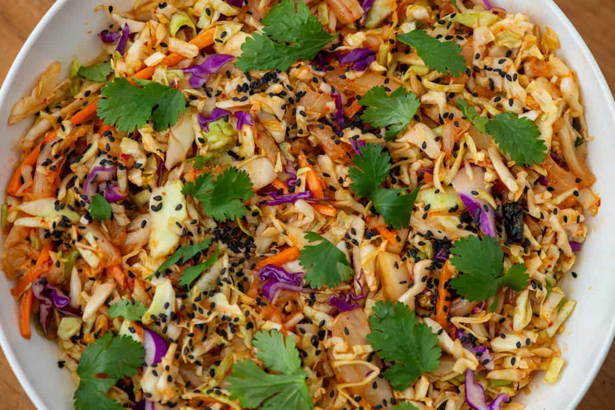 Overhead view of partial bowl of kimchi slaw garnished with black sesame seeds and cilantro