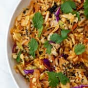 Partial bowl of kimchi slaw garnished with black sesame seeds and cilantro