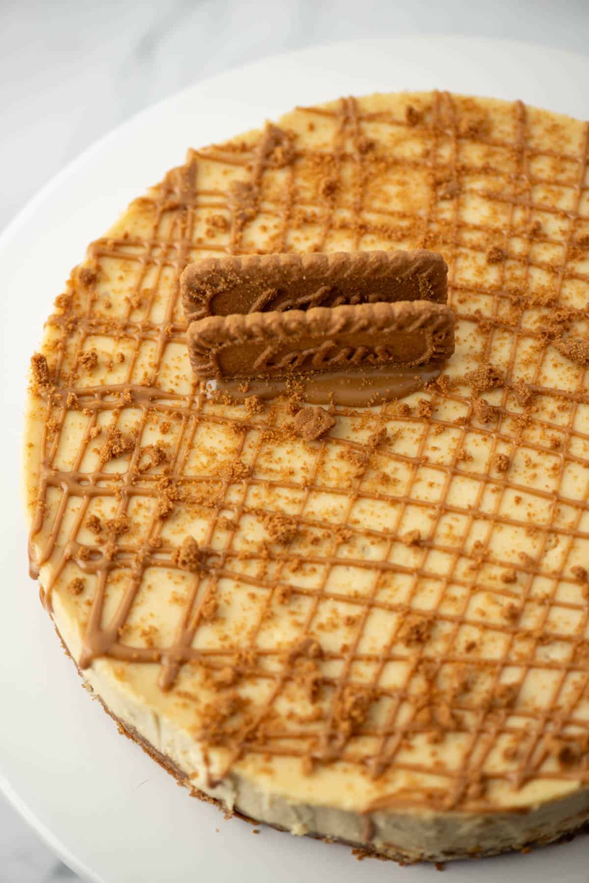 Overhead view of partial Biscoff Cookie Butter cheesecake decorated with cookie butter drizzle and crumbled Biscoff cookies