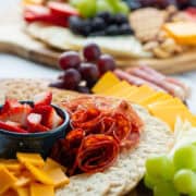 Side view of a charcuterie board with cheeses, meats, fruits and crackers with another full charcuterie board in the background