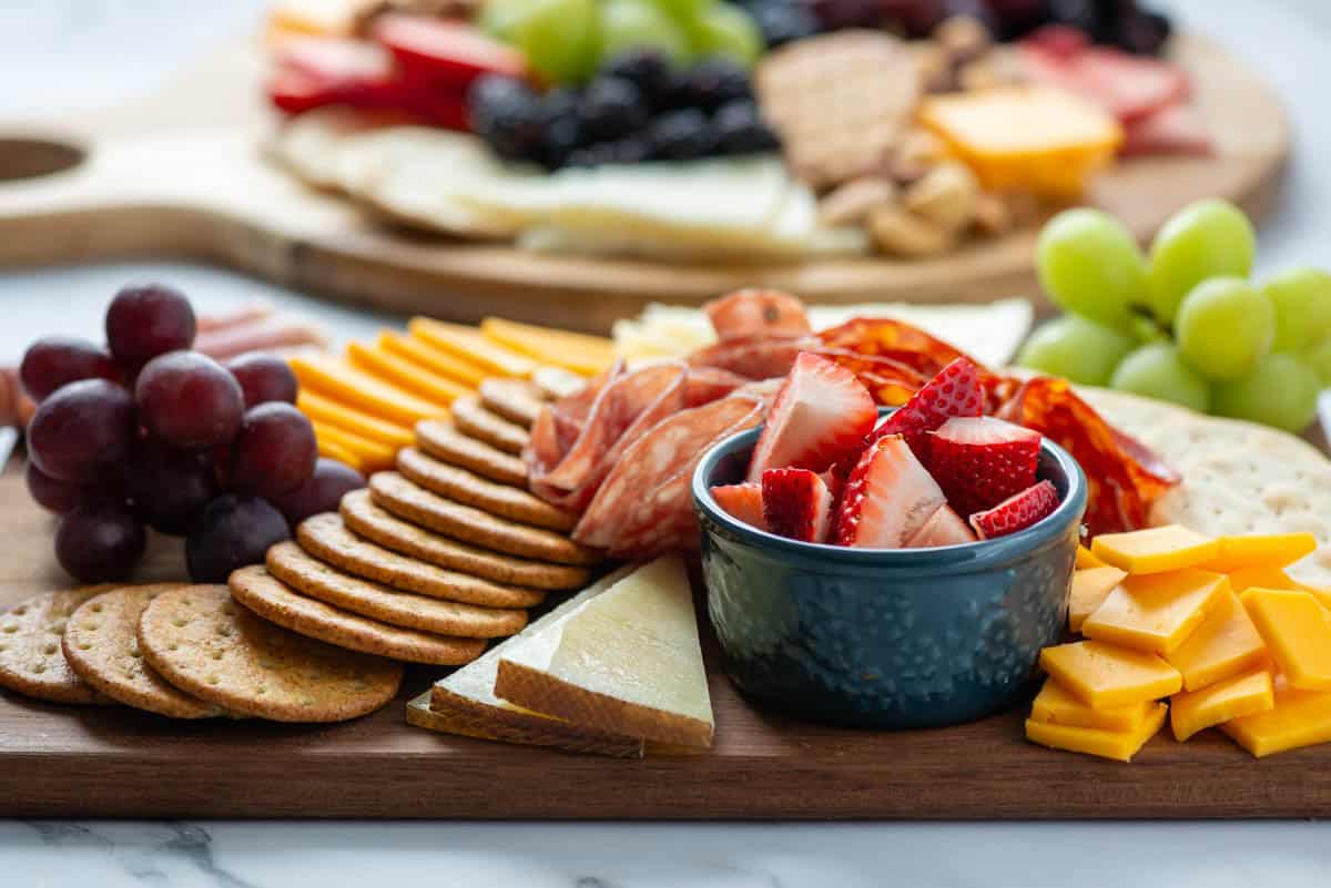 Side view of a full charcuterie board with another full charcuterie board in the background