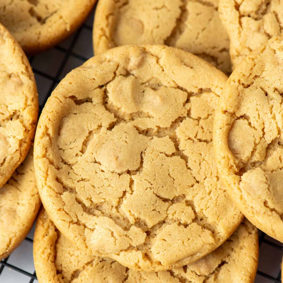 Close up photo of giant peanut butter cookies randomly stacked on a cooling rack