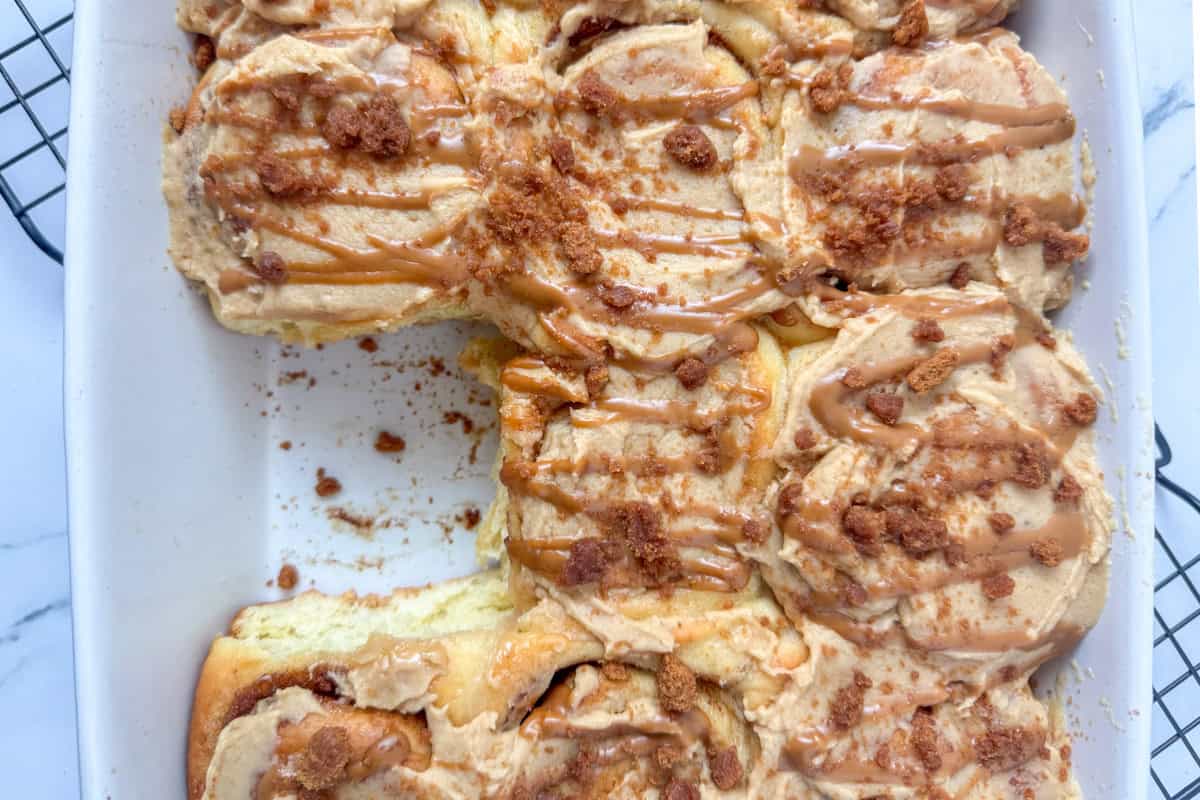 Overhead view of a pan of Biscoff cinnamon rolls with one missing