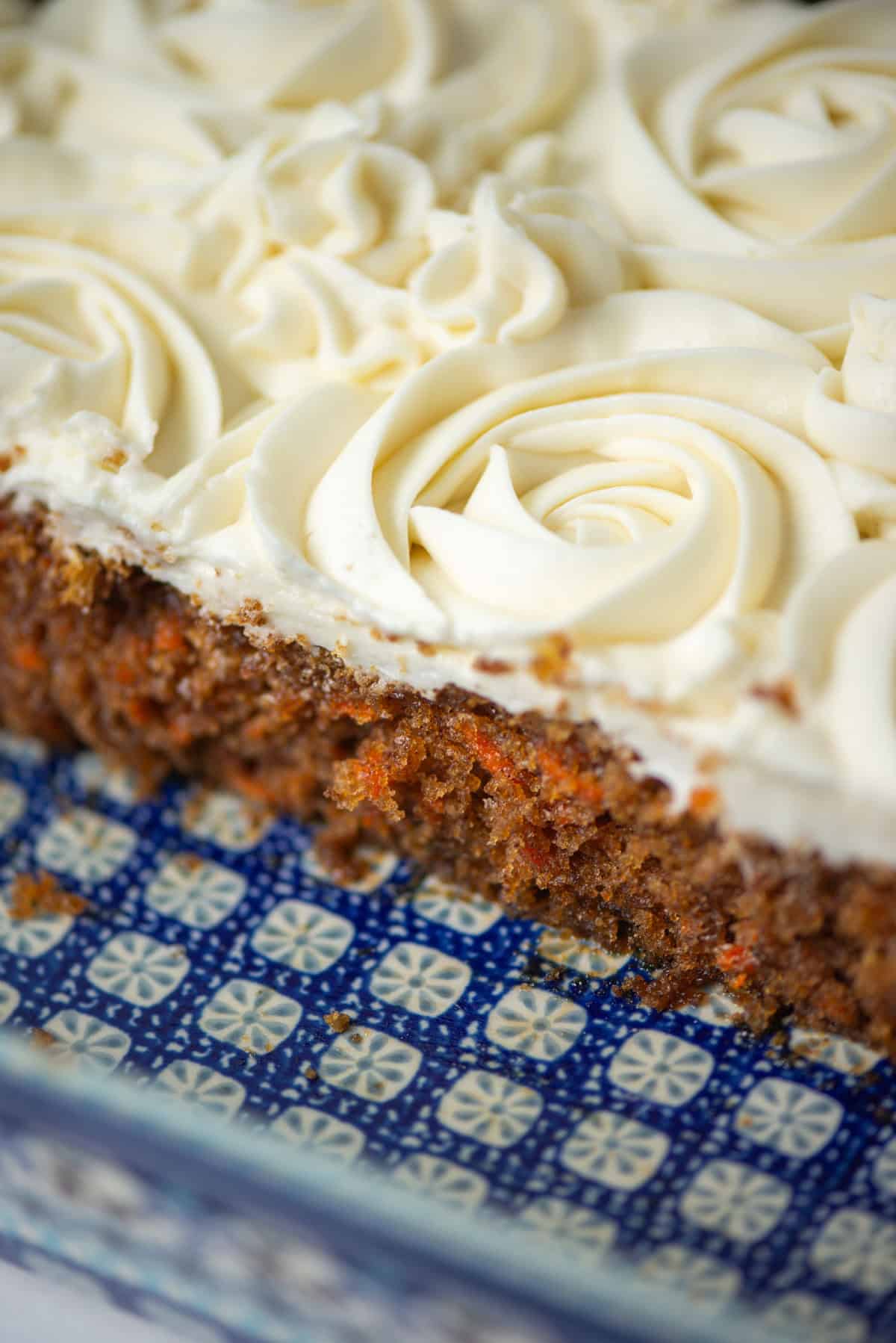 Overhead view of carrot cake in a 9x13 baking pan with a few pieces missing