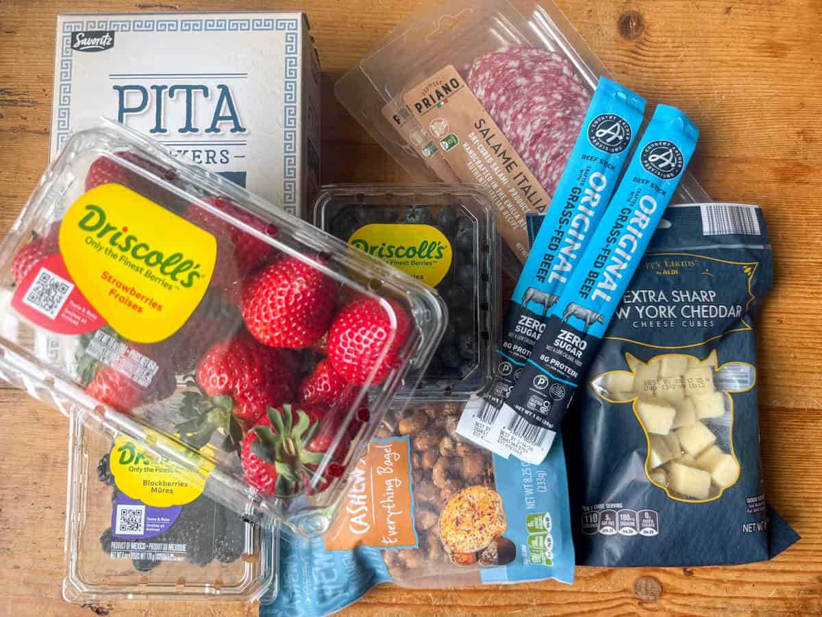Close up photo of a Charcuterie Board made from ingredients bought at Aldi: strawberries, blackberries, blueberries, cheese cubes, pita chips, nuts, meat sticks and cured meats
