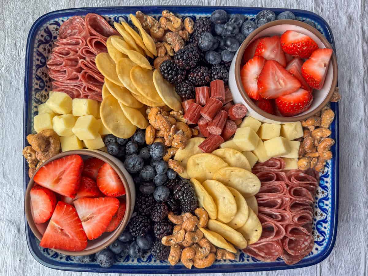 Overhead photo of a Charcuterie Board made from ingredients from Aldi: strawberries, blackberries, blueberries, cheese cubes, pita chips, nuts, meat sticks and cured meats